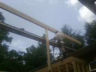 Carpenter setting a ridge beam over a new addition frame — Ice Dam Removal by Roofing Brothers in Van Etten