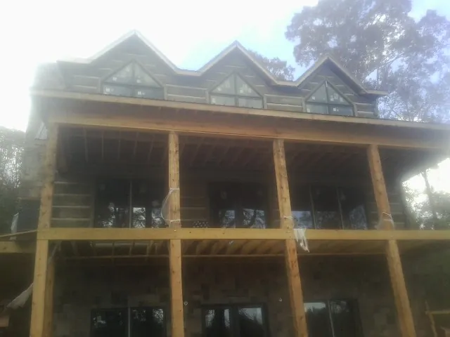 Dormers and porch framing on a large log home under construction — Roof Coating work by our crew in Van Etten