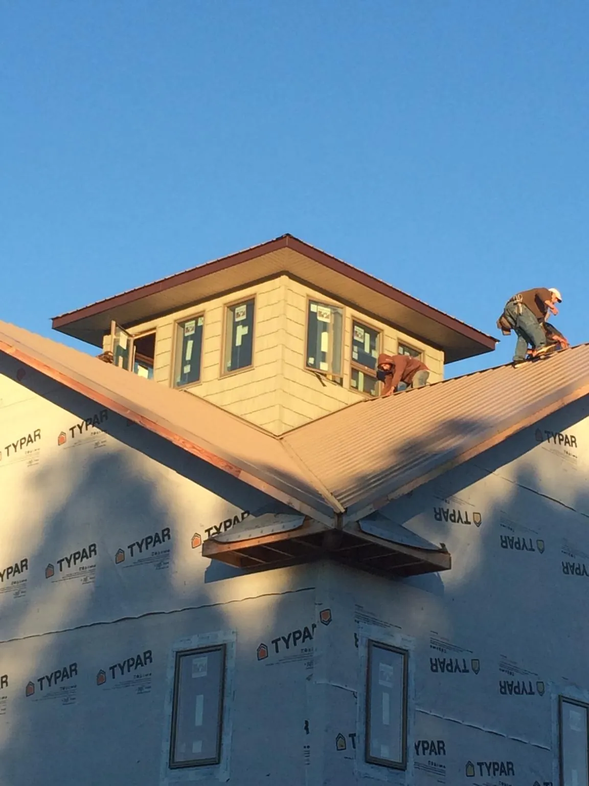 Roofers working around a rooftop cupola on a new metal roof at sunset — Roof Waterproofing in Van Etten by Roofing Brothers